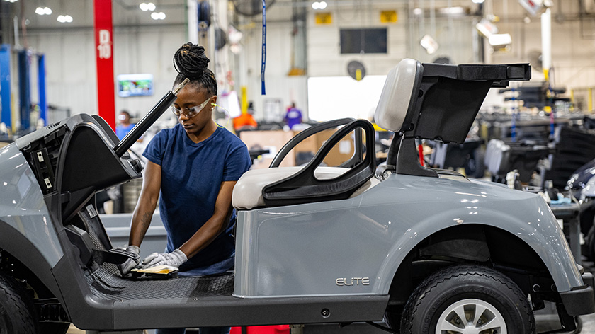 An E-Z-GO employee works on the frame of a vehicle on the production line.