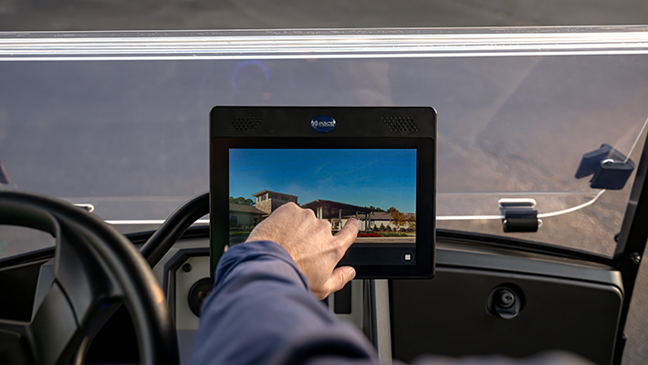 A hand uses the Pace Technology touch screen in an E-Z-GO golf cart.
