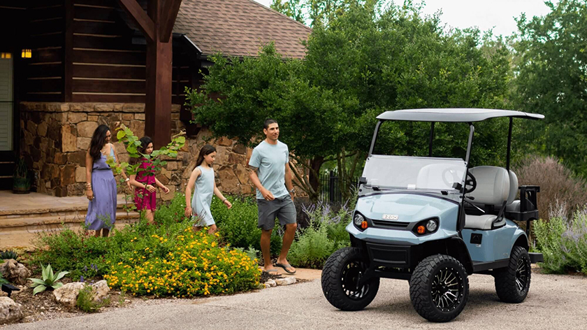 A family walks toward an E-Z-GO golf cart.