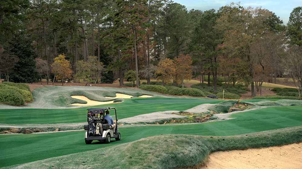 An E-Z-GO driving across a golf course turf.